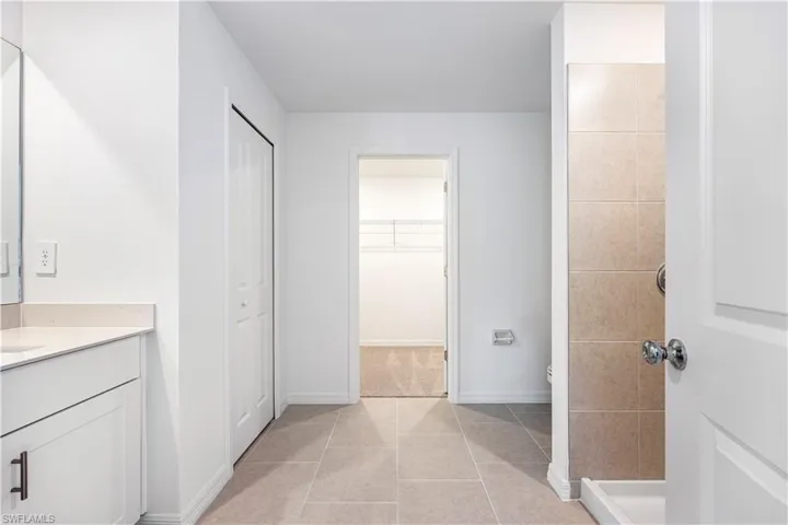 Bathroom featuring vanity, a walk in closet, and light tile patterned floors