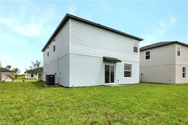 Rear view of house with a lawn and stucco siding