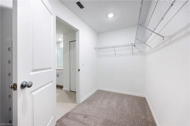 Walk in closet featuring light colored carpet and light tile patterned floors