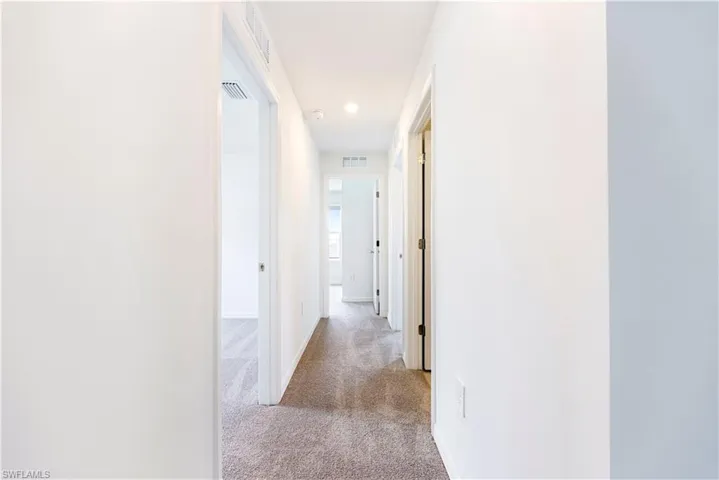 Corridor with light colored carpet and recessed lighting