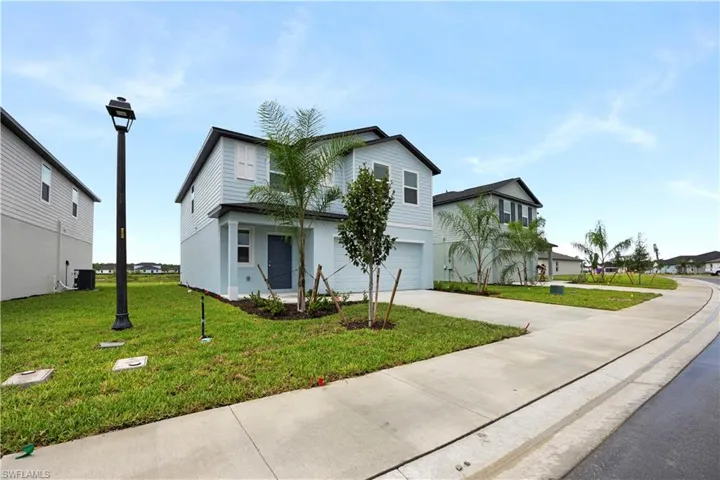 Traditional-style house with a front yard, an attached garage, and driveway