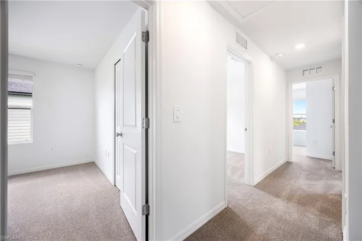 Corridor featuring light colored carpet, plenty of natural light, and recessed lighting