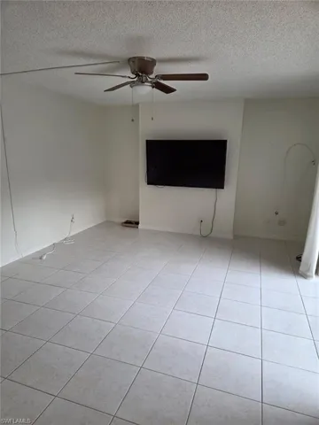 Empty room featuring ceiling fan, a textured ceiling, and light tile patterned flooring