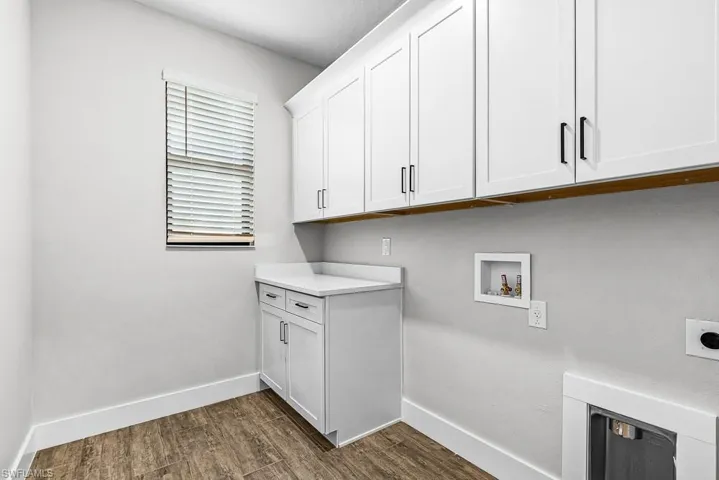Washroom with cabinet space, dark wood-style floors, and washer hookup