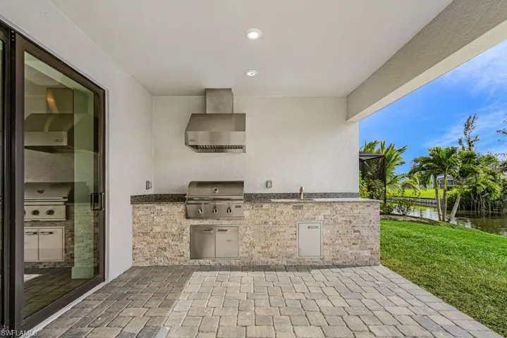 View of patio with a water view, ceiling fan, and exterior kitchen
