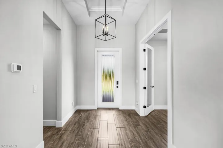 Foyer entrance with wood tiled floors, a chandelier, and a raised ceiling
