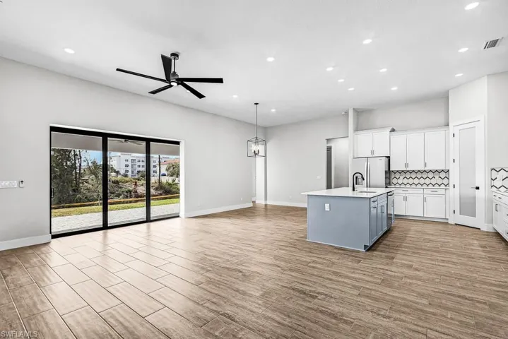 Kitchen with white cabinetry, pendant lighting, open floor plan, gray cabinets, and an island with sink