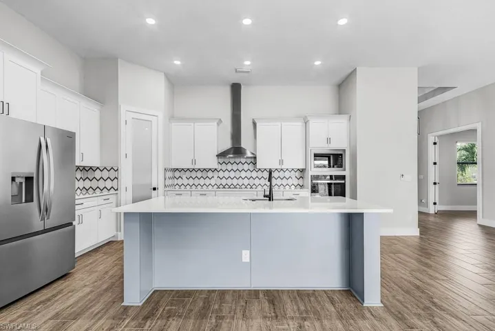 Kitchen with stainless steel appliances, white cabinets, wall chimney exhaust hood, dark wood finished floors, and recessed lighting
