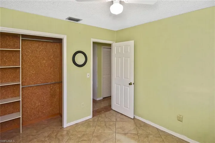 Unfurnished bedroom featuring a textured ceiling, a closet, light tile patterned floors, and a ceiling fan