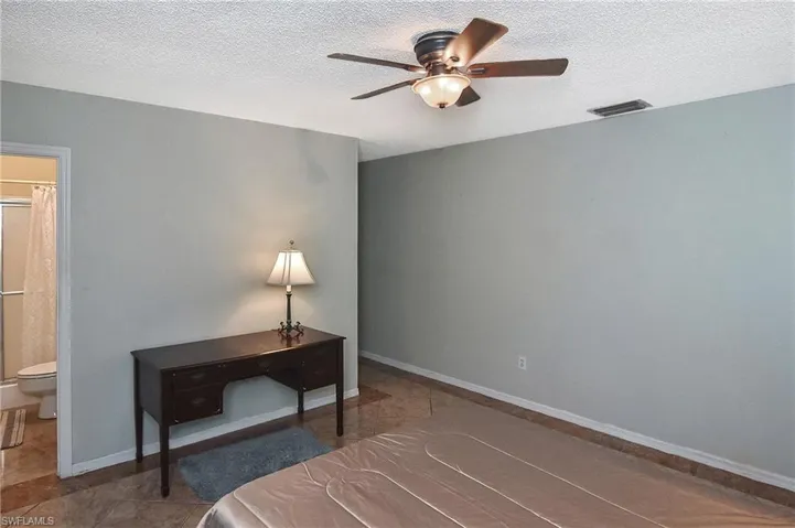 Bedroom featuring tile patterned floors, a ceiling fan, a textured ceiling, and ensuite bathroom