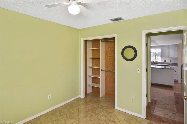 Unfurnished bedroom with a textured ceiling, a closet, light tile patterned floors, and ceiling fan
