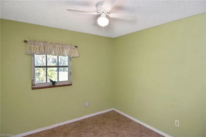Tiled empty room featuring a textured ceiling and ceiling fan