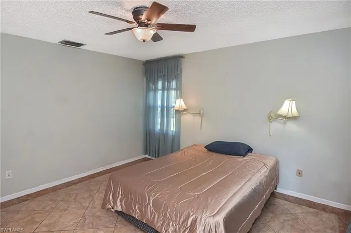 Bedroom featuring a textured ceiling, light tile patterned flooring, and ceiling fan