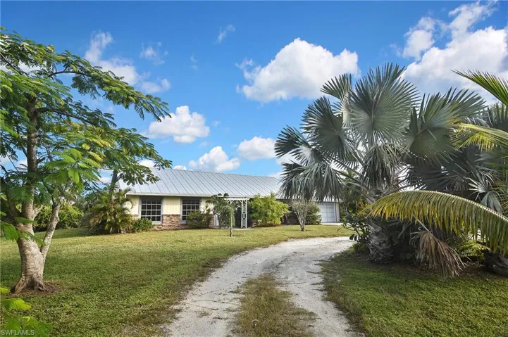 View of front of house featuring a front lawn, driveway, and stone siding