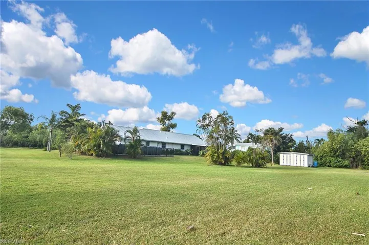 View of green lawn featuring view of wooded area
