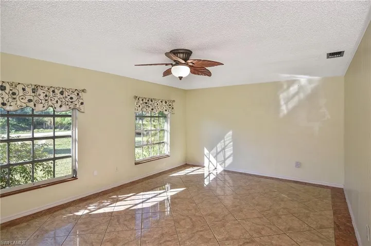 Tiled spare room featuring a textured ceiling and a ceiling fan