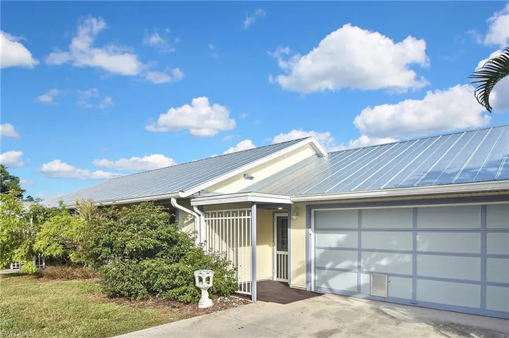 View of front of home with a metal roof, concrete driveway, and an attached garage