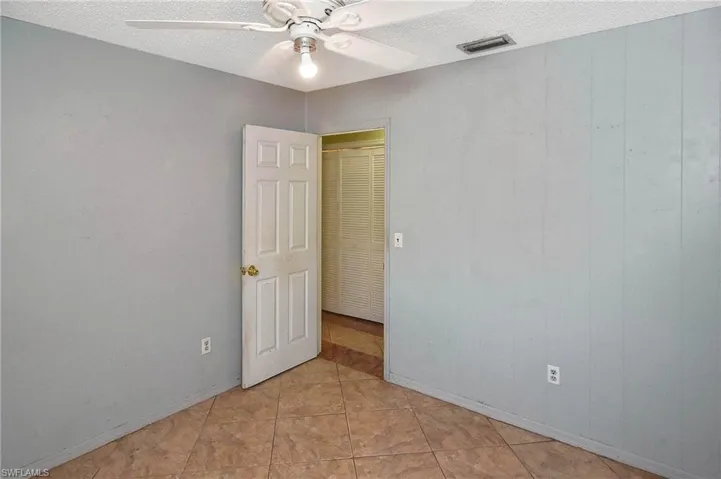 Unfurnished room with a textured ceiling, light tile patterned flooring, and ceiling fan