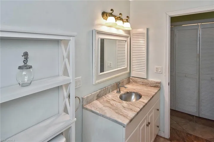 Bathroom featuring a closet, vanity, and dark tile patterned floors
