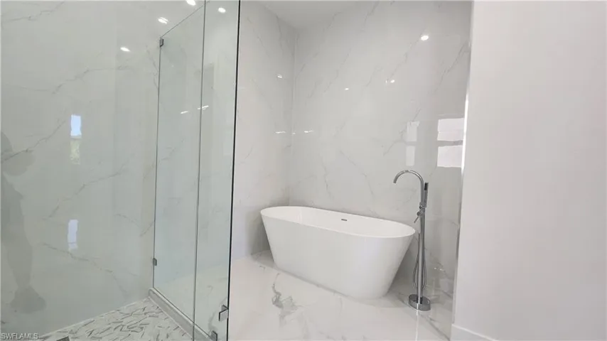 Bathroom with shower with separate bathtub and tile walls