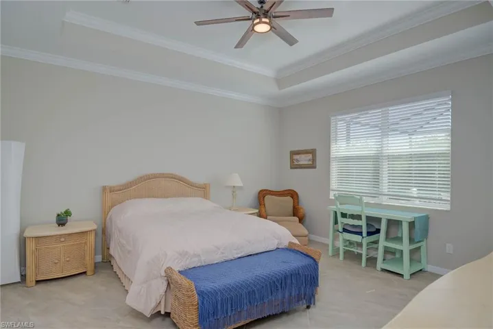 Bedroom featuring a tray ceiling, crown molding, and ceiling fan
