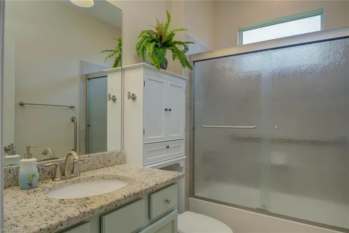 Bathroom with shower / bath combination with glass door and vanity