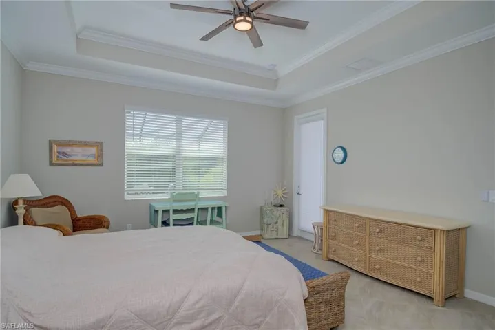 Bedroom with a tray ceiling, ceiling fan, and ornamental molding