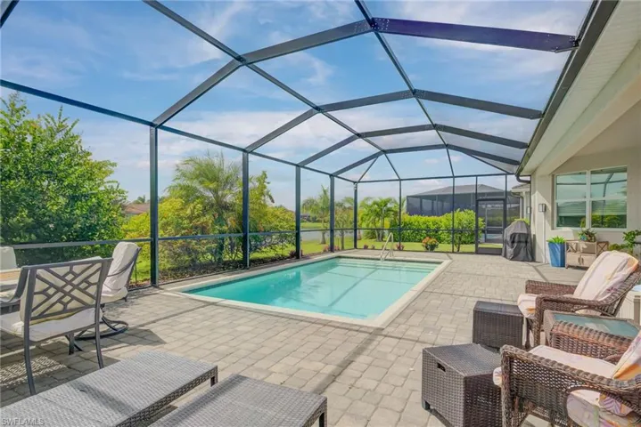 Outdoor pool with a sunroom, glass enclosure, and a patio area