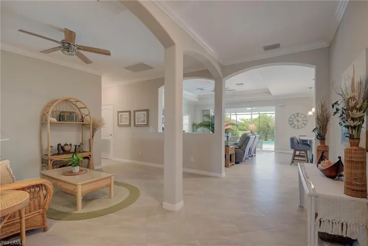 Foyer featuring ornamental molding, arched walkways, a ceiling fan, and light tile patterned floors
