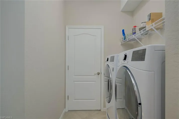 Laundry room with washing machine and dryer and light tile patterned flooring
