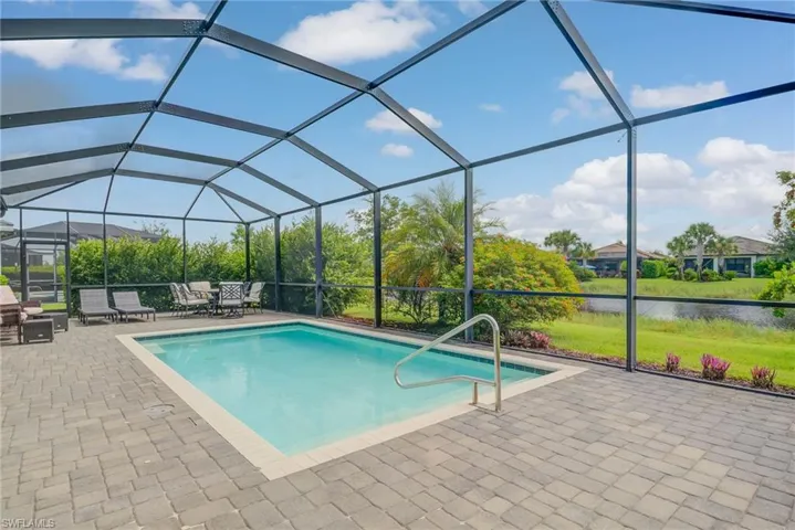 Swimming pool featuring a sunroom, glass enclosure, a water view, and a patio