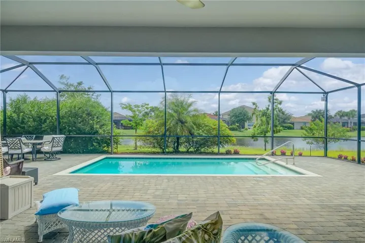 Swimming pool featuring a sunroom, a patio, a lanai, and a water view