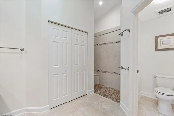 Bathroom featuring tile flooring, tiled shower, and toilet