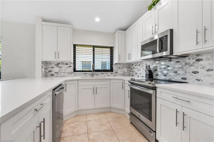 Kitchen featuring tasteful backsplash, stainless steel appliances, light tile floors, sink, and white cabinets
