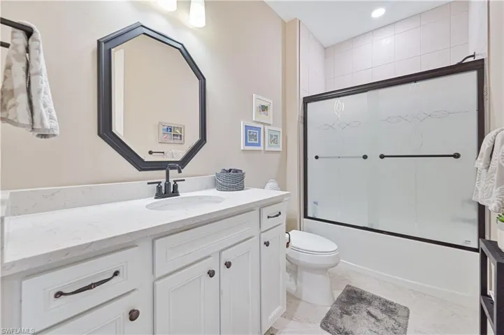 Bathroom with vanity, toilet, shower / bath combination with glass door, and recessed lighting
