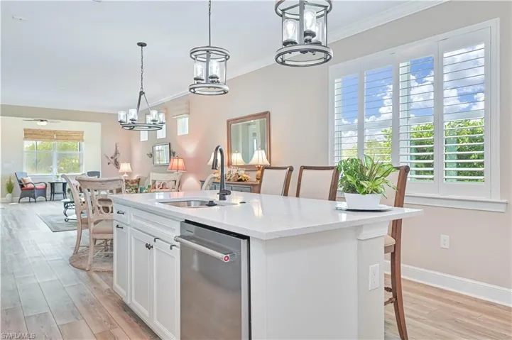 Kitchen featuring a chandelier, a sink, crown molding, stainless steel dishwasher, and open floor plan