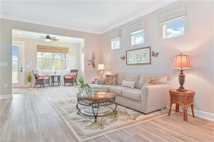 Living room with wood finished floors, ornamental molding, baseboards, and a ceiling fan