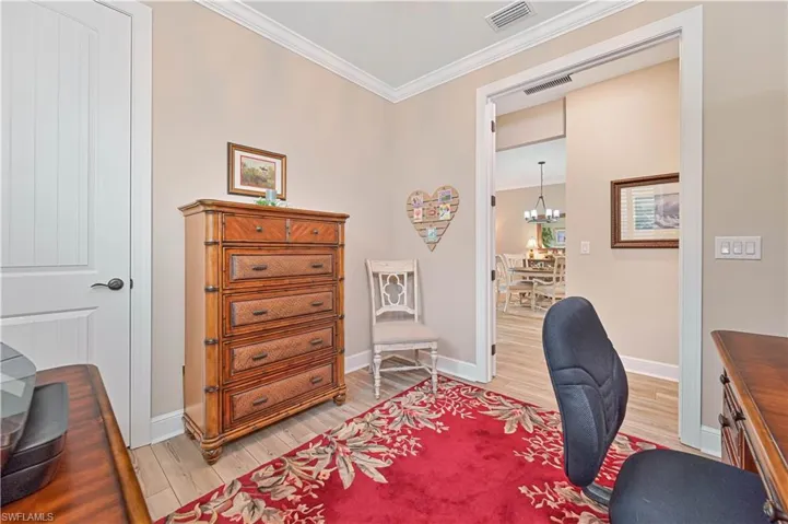 Office area with light wood finished floors, crown molding, a chandelier, and baseboards