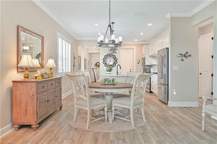 Dining room with a chandelier, baseboards, light wood finished floors, ornamental molding, and recessed lighting