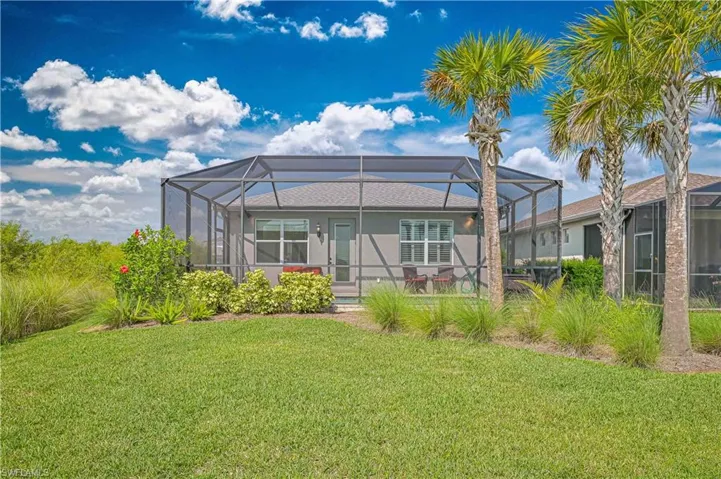 Back of property with a lawn, stucco siding, and glass enclosure