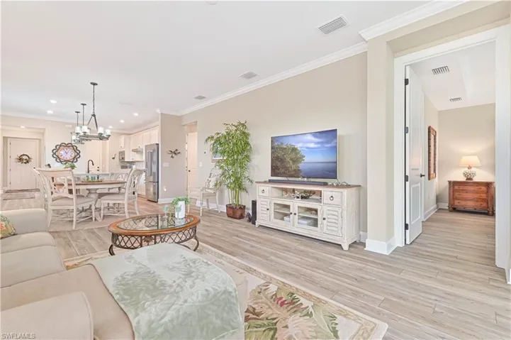 Living room featuring light wood-style flooring, baseboards, ornamental molding, recessed lighting, and a chandelier