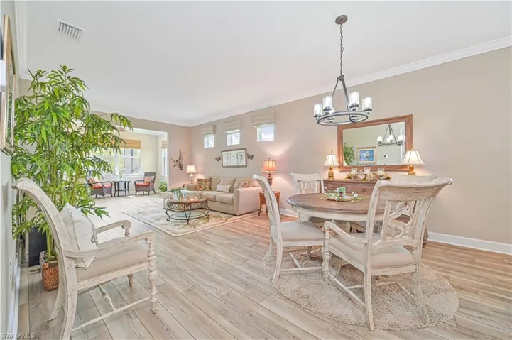 Dining space featuring ornamental molding, a chandelier, wood finished floors, and baseboards