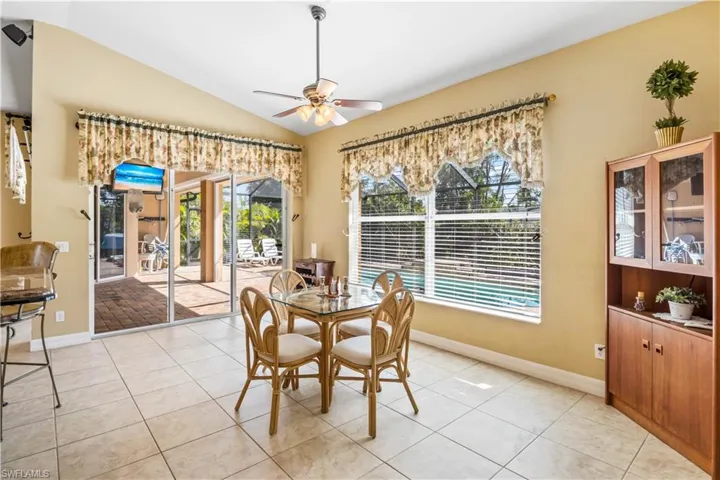 Dining room with lofted ceiling, light tile patterned floors, and ceiling fan