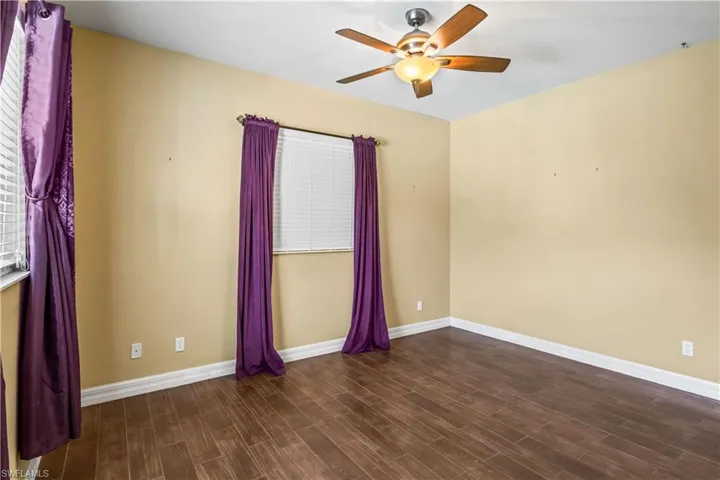 Empty room with ceiling fan and dark hardwood / wood-style floors