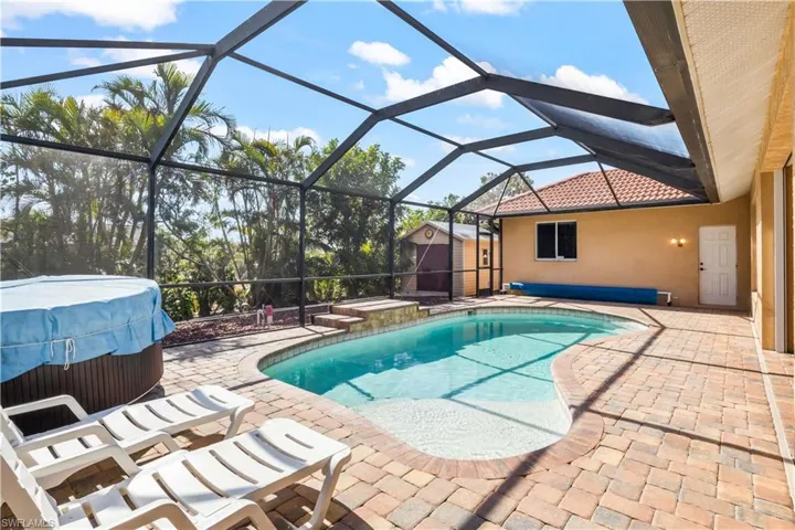 View of pool with a storage shed, a lanai, a patio area, and a hot tub