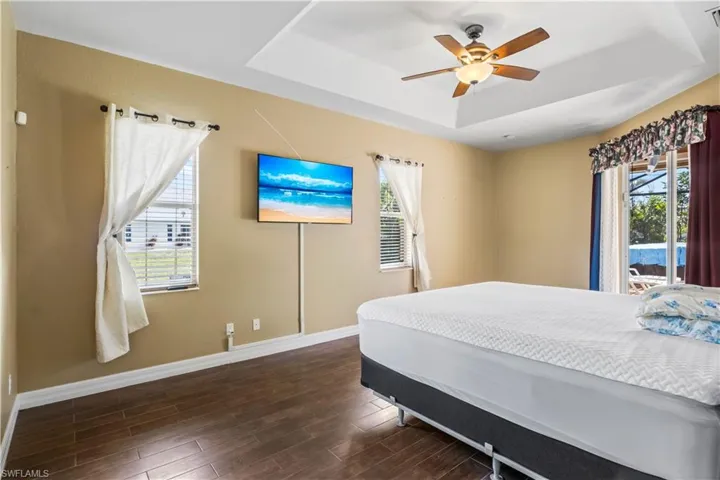 Bedroom with a tray ceiling, dark hardwood / wood-style floors, and ceiling fan