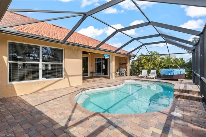 View of pool featuring a hot tub, a patio, ceiling fan, and glass enclosure