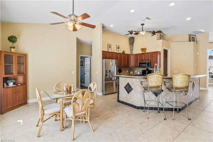 Kitchen with light tile patterned flooring, a kitchen bar, tasteful backsplash, appliances with stainless steel finishes, and ceiling fan
