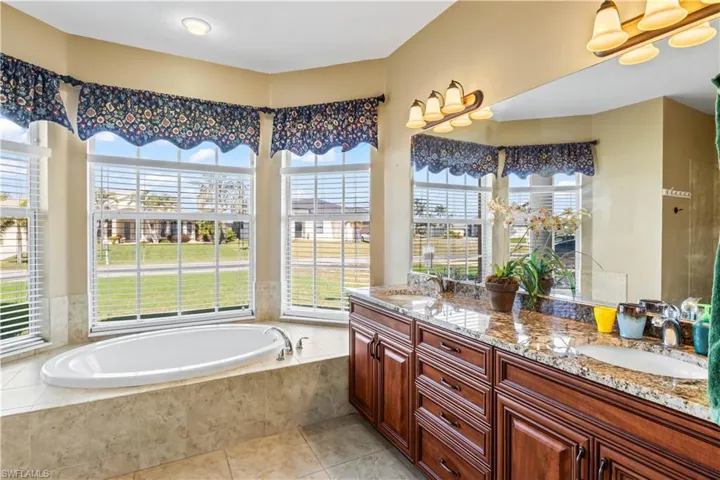 Bathroom featuring vanity, tile patterned flooring, and tiled bath