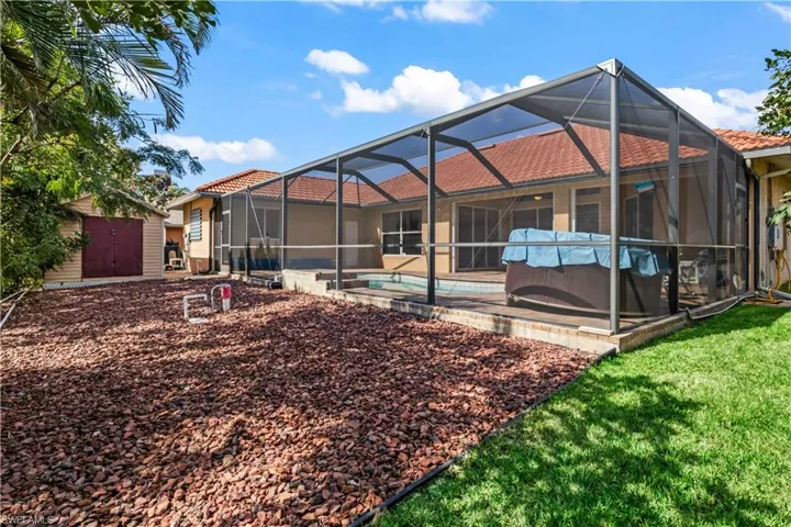 Back of property featuring a storage shed, a lanai, and a patio